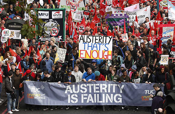 Demonstrators hold placards before the start of a protest march organised by the Trades Union Congress in central London.