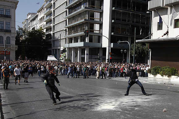 Demonstrators throw objects at riot police at an anti-austerity march in central Athens, Greece.