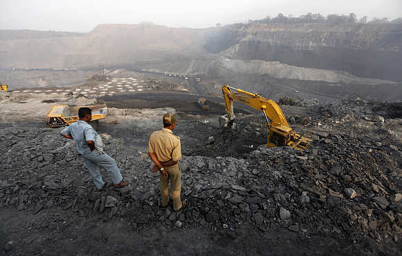 A policeman and a worker watch coal being loaded on a truck in the Mahanadi coal fields, near Talcher town, in Orissa.