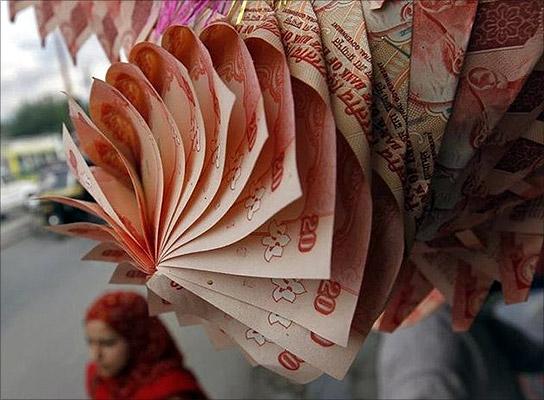 A Kashmiri woman walks under a garland made of rupee notes on display at a market in Srinagar. 