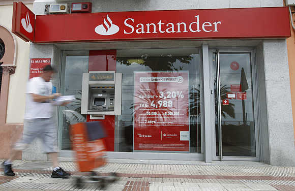 A postman walks pass a Santander's bank office in El Masnou, near Barcelona, Spain.