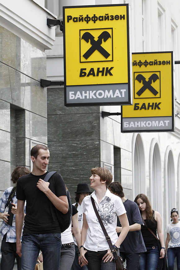Pedestrians walk past a Raiffeisen Bank branch in Moscow.