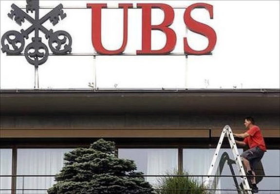A worker climbs on a ladder under the logo of Swiss bank UBS at the company's headquarters in Zurich.
