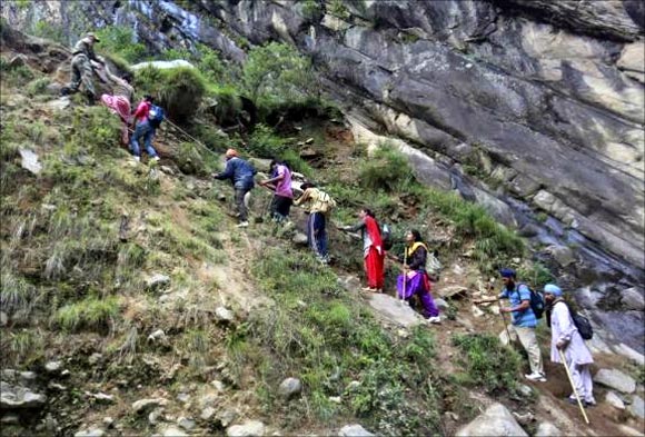 Pilgrims are helped to climb over a hill by Army soldiers during a rescue operation at Govindghat in Uttarakhand.
