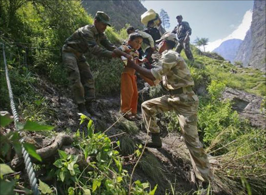 A child is carried by soldiers to help him climb down a hill during a rescue operation at Govindghat in Uttarakhand.