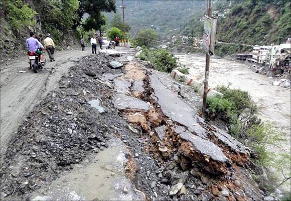 People walk along a damaged road after heavy rains in Uttarakhand.