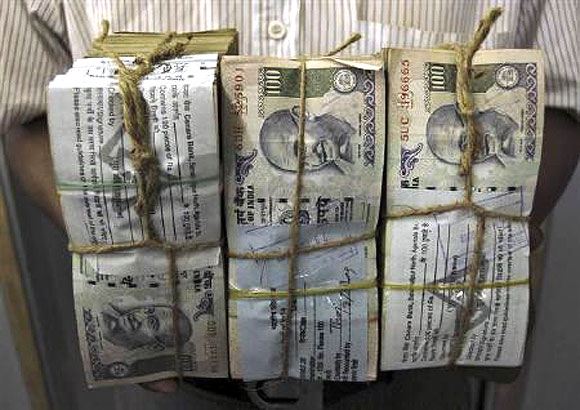 An employee carries bundles of Indian currency notes inside a bank in Agartala.