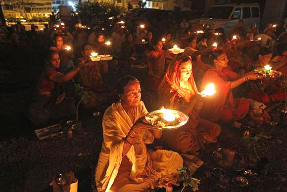 People carry oil lamps as they pray for the flood victims.
