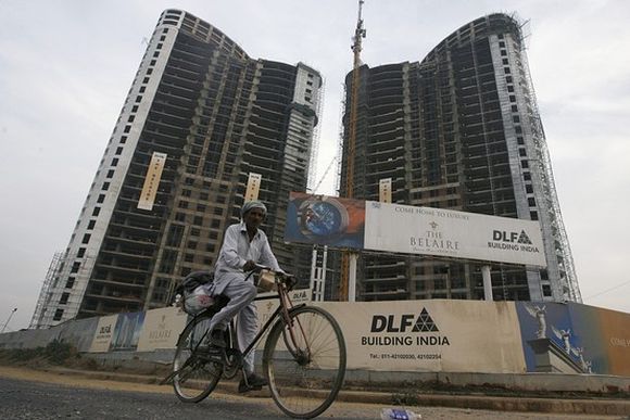 A man cycles past the construction site of a residential apartment building by Indian property developer DLF.