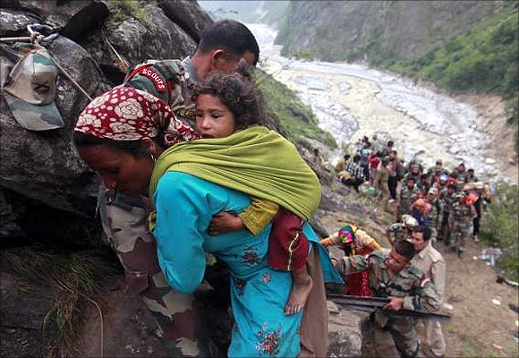Soldiers assist a woman carrying a child on her back during rescue operations in Govindghat in the Himalayan state of Uttarakhand.