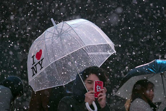 Chelsea House of St Louis takes pictures in Times Square as snow falls in New York City.
