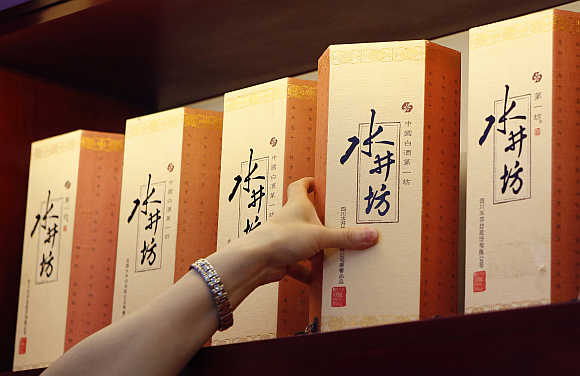 A clerk picks up a box of Sichuan Swellfun baijiu at a liquor shop in Beijing.