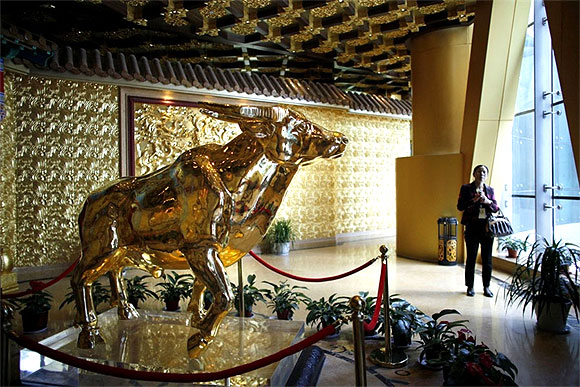 A woman stands next to a gold statue of an ox.