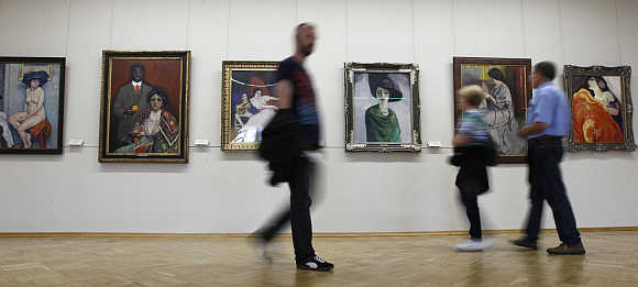 Visitors walk past impressionist paintings in the State Hermitage Museum in St Petersburg, Russia.