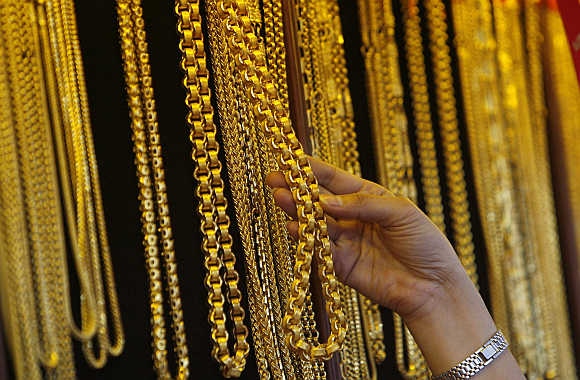 A shopkeeper picks up a gold chain for a customer to try in Bangkok's Chinatown.