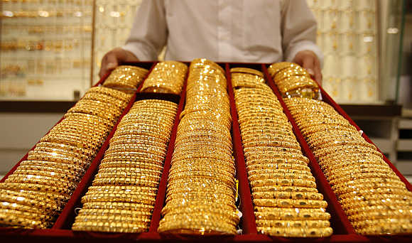 A shop attendant displays a tray of gold bangles at a jewellery store in Singapore.