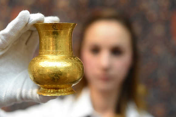 A member of Sotheby's staff holds a 14th century Central Asian gold cup with an estimated value of $48,600-81,000 in London.