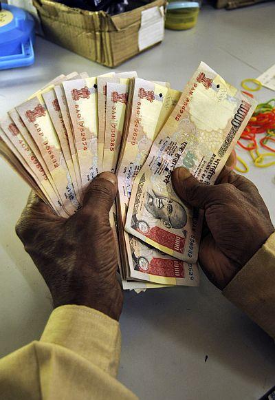 A bank employee counts currency notes at a cash counter in Agartala.