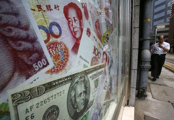Photos of yuan (top) and US dollar banknotes are displayed at a money exchange in Hong Kong.
