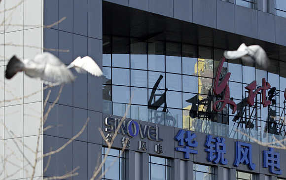 Pigeons fly past the company logo of Sinovel Wind outside its head office in Beijing.