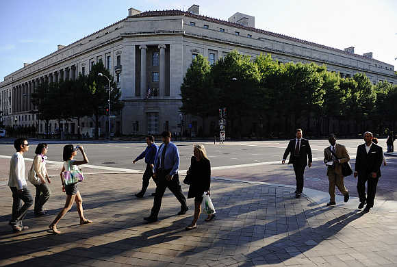 Pedestrians walk on the sidewalk across the US Department of Justice headquarters building on Pennsylvania Avenue in Washington, DC.