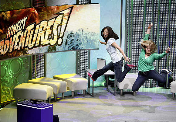 Assistants demonstrate the game 'Kinect Adventures' for Kinect for Xbox 360 during a media briefing at the Wiltern theatre in Los Angeles.