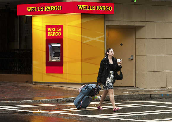 A woman crosses the street near a Wells Fargo automated teller machine in Charlotte, North Carolina, United States.