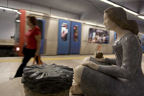 A passanger walks out of a Lisbon subway station decorated with sculptures.