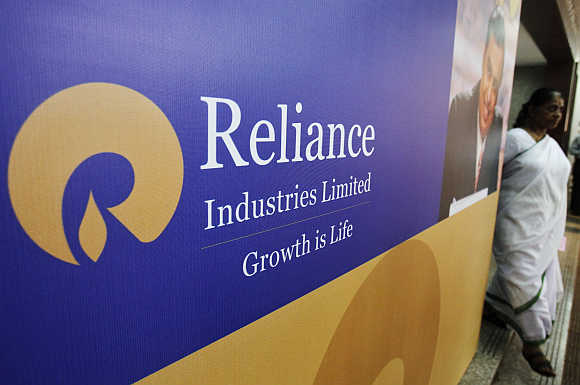 A woman walks past a poster of Reliance Industries in Mumbai.
