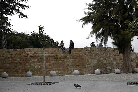 Two girls talk sitting on the Venetian Walls surrounding the old town of capital Nicosia.