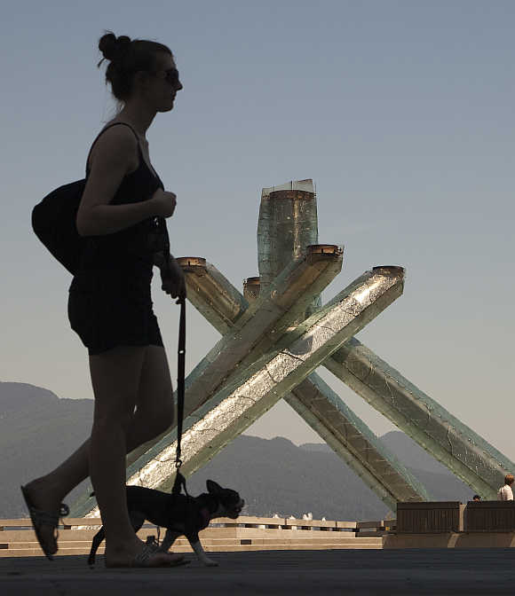 A woman walks past the Olympic Cauldron, one of the few signs left of the 2010 Olympic Winter Games held in Vancouver, British Columbia.