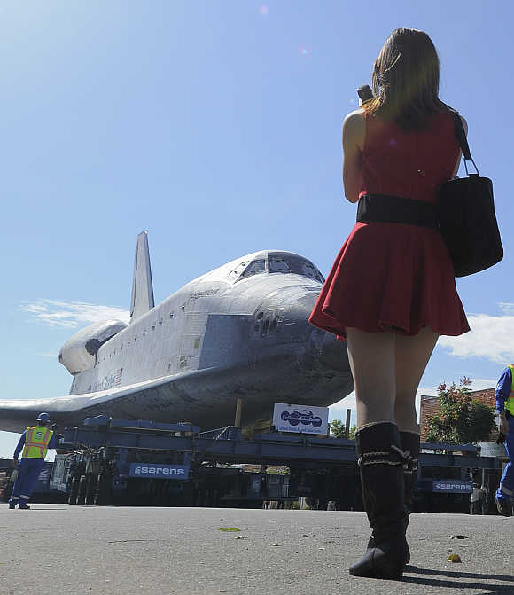 A woman watches as Space Shuttle Endeavour makes it way during its final ground journey in Los Angeles, California.