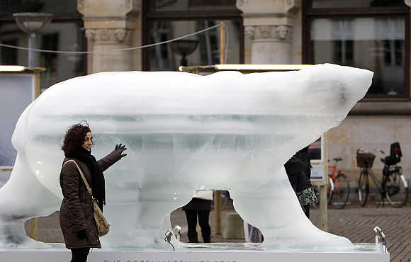 A woman touches an ice sculpture of a polar bear in downtown Copenhagen, Denmark.