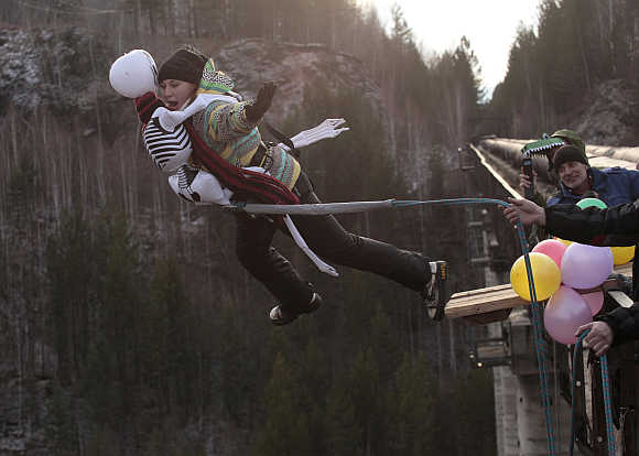 A woman, dressed in a Halloween costume, takes a rope jump from a 144 feet high water pipe bridge in the Siberian Taiga area outside Krasnoyarsk, Russia.