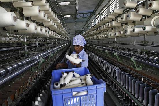 A worker handles the production of yarn on a yarn-spinning equipment at a factory in Coimbatore.