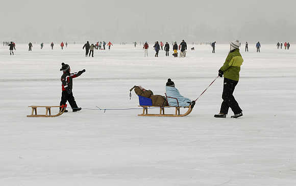 A woman pulls two sleds on the frozen Lake Pfaeffikersee some 20 km east of Zurich, Switzerland.