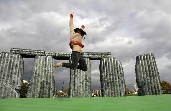 A woman jumps on 'Sacrilege, 2012' art works by Jeremy Deller at the Esplande des Invalides in Paris, France.