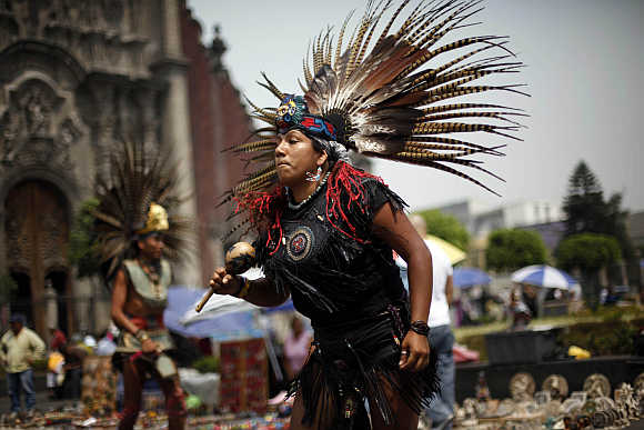 A group performs an Aztec dance for tourists outside the Metropolitan Cathedral in Mexico City.