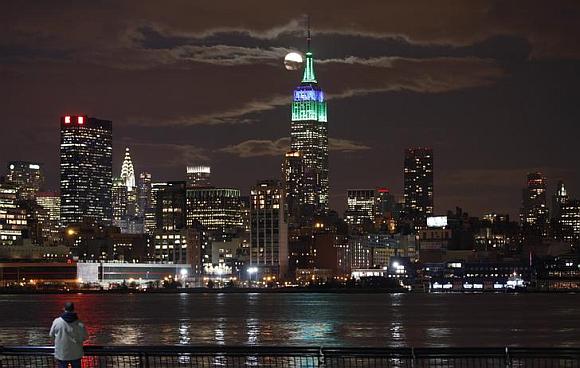 A full moon rises behind the Empire State Building in New York.