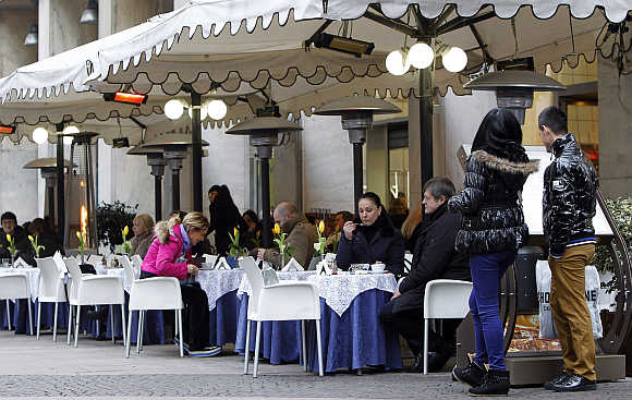 A couple looks at a restaurant menu in downtown Milan, Italy.