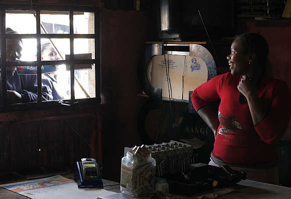 Trader Nono Dawane greets customers at her small shop selling cigarettes and cold drinks in Cape Town's Khayelitsha township, South Africa.
