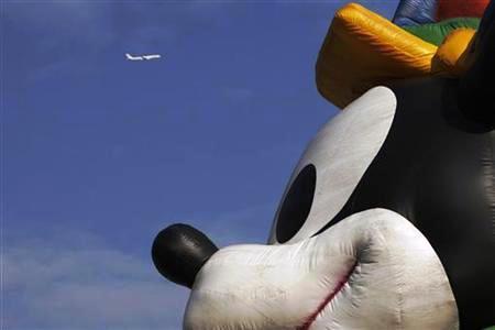 A plane flies past a musical parade at Hong Kong Disneyland.