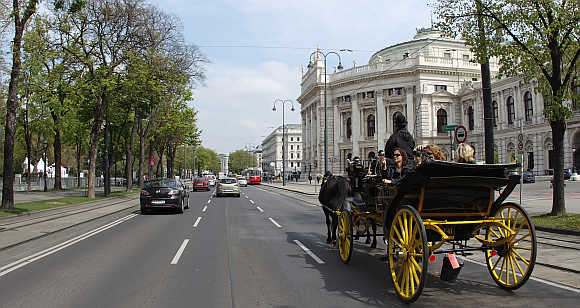 A traditional Fiaker horse carriage passes Burgtheater theatre on Dr.-Karl-Lueger-Ring street in Vienna.