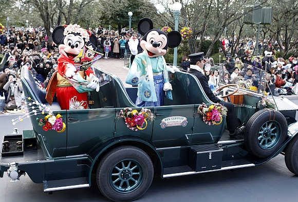 Disney cartoon characters Mickey, right, and Minnie Mouse, left, dressed in kimonos, wave from an open car at Tokyo Disneyland in Urayasu, Japan.