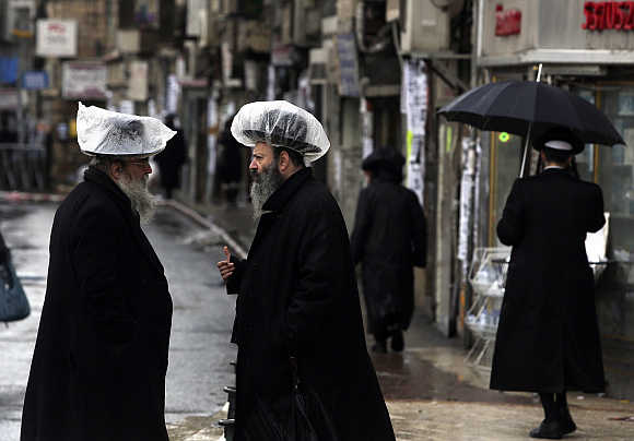 Ultra-Orthodox Jews, wearing hats covered with plastic against the rain, talk in Jerusalem's Mea Shearim neighbourhood, Israel.