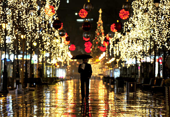 A man walks near trees illuminated with Christmas lights in Skopje, Macedonia.