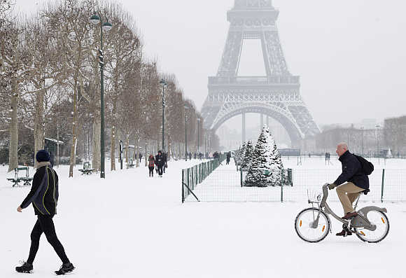 A man rides Velib, a self-service public bicycle, as he makes his way along a snow-covered area at the Champs de Mars near the Eiffel Tower in Paris, France.