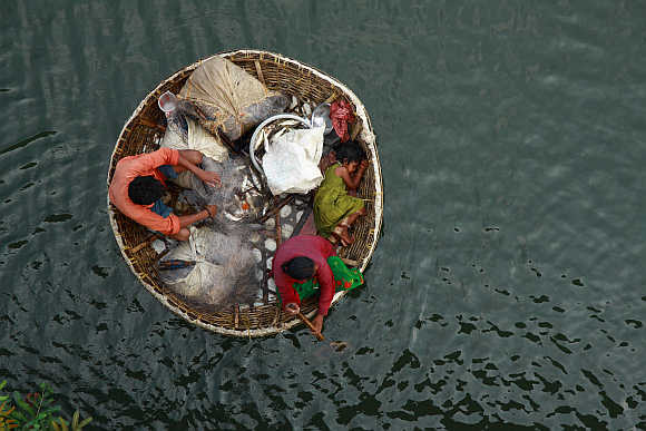 A fisherman arranges a fishing net as his wife paddles their boat in the waters of the Periyar river in Kochi, India.