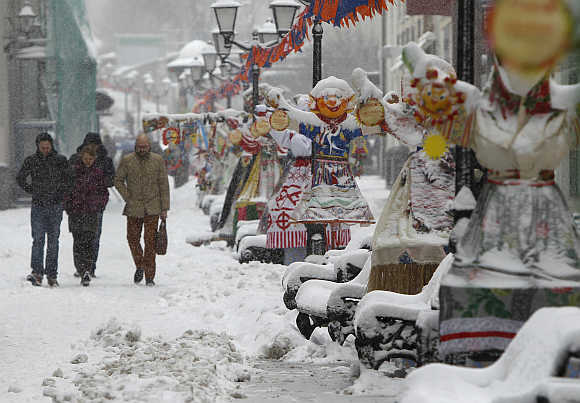 People walk past traditional Maslenitsa spring festival decorations during a snowstorm in Moscow, Russia.
