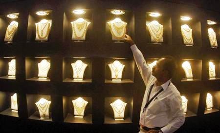 An employee displays gold necklaces at the 'Gem and Jewellery India International Exhibition 2010' (GJIIE) in Chennai.